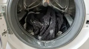 Asciugamani scuri con residui di detersivo dentro una lavatrice aperta