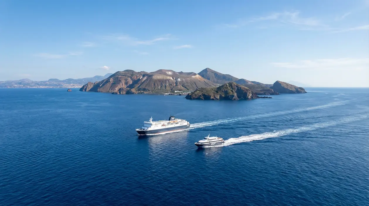 Traghetto e aliscafo in navigazione verso le isole Eolie su mare calmo e cielo sereno