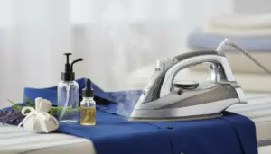 Ferro da stiro a vapore su camicia blu con flaconi di profumo e sacchetto profumato alla lavanda