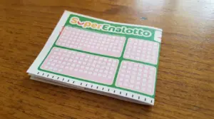 Schedina del SuperEnalotto appoggiata su un tavolo di legno