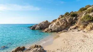 Spiaggia sabbiosa con mare turchese e rocce, in una giornata soleggiata e tranquilla