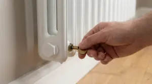 Mano che spurga un termosifone con la chiave della valvola per eliminare aria e migliorare il riscaldamento